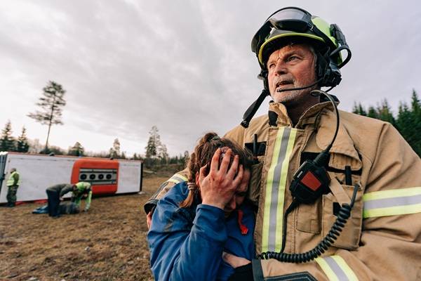 En hjelpearbeider som holder rundt en jente hvor scenen er tatt fra en trafikkulykke. Foto: Samuel Anderson