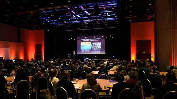 Bilde av plenumssalen hvor det sitter mange mennesker og ser mot lerret fremst i salen på konferansen Lillehammer Lifelong Learning.